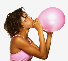 Девушка надувает розовый воздушный шар